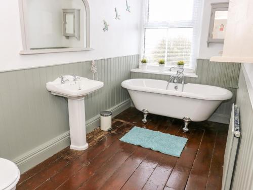 uma casa de banho com uma banheira branca e um lavatório. em Canalside Cottage em Kildwick