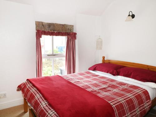 a bedroom with a red bed and a window at Sunny Bank View in Bradwell