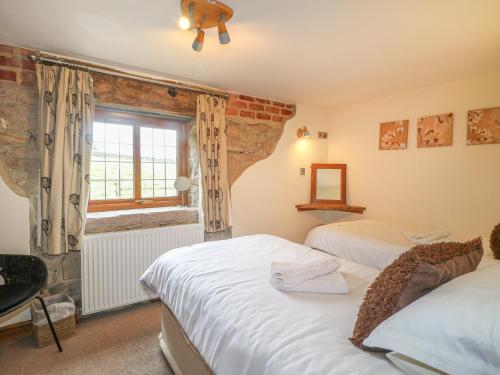 a bedroom with two beds and a window at Fletchers Barn in Alderwasley