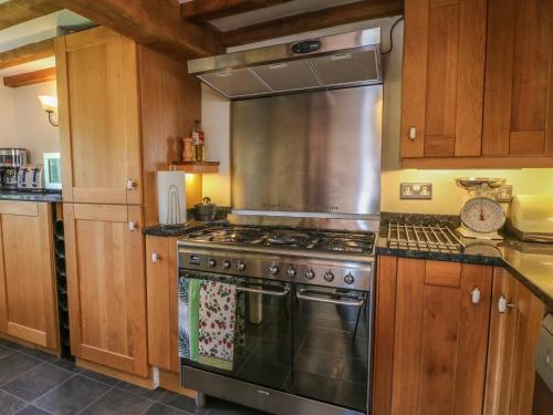 a kitchen with a stainless steel stove and wooden cabinets at The Milk House in Wirksworth