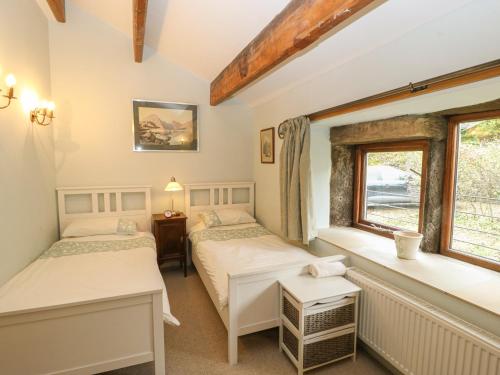 two beds in a room with two windows at Salter Rake Gate Cottage in Walsden