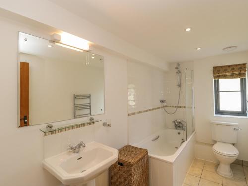 een badkamer met een wastafel, een bad en een toilet bij Rowdens Barn in Winterborne Stickland