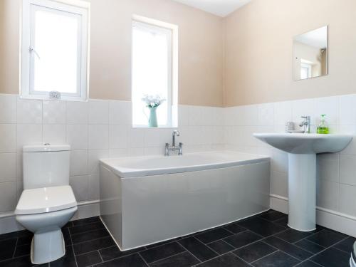 a white bathroom with a sink and a toilet at Tomeg in Amble