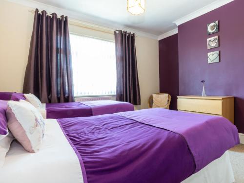 two beds in a bedroom with purple walls and a window at Tomeg in Amble