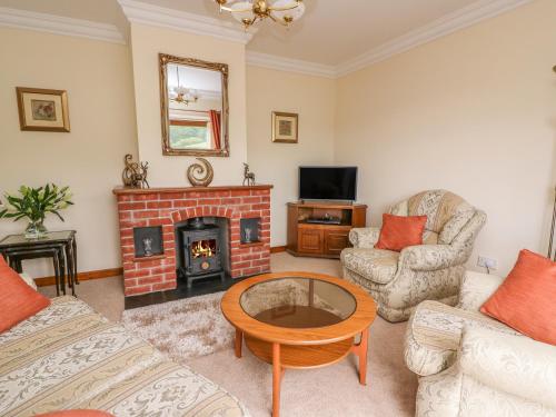 a living room with a brick fireplace and a table at Drainbyrion Farm House in Van