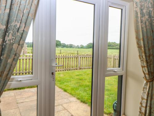 an open door with a view of a field at Tawny Owl Barn in Shipdham