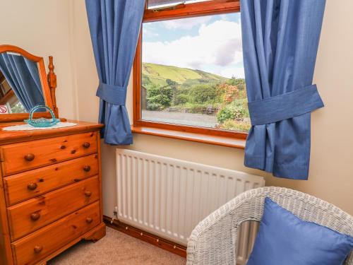 a bedroom with a window and a chair and a dresser at Drainbyrion Farm House in Van