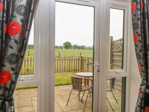 a view from the door of a patio with a table at Snowy Owl Barn in Shipdham