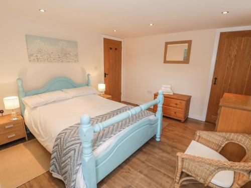 a bedroom with a blue bed and a chair at Hendoll Cottage 2 in Fairbourne