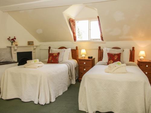 two beds with white sheets in a room with a fireplace at Penymaes in Chirk