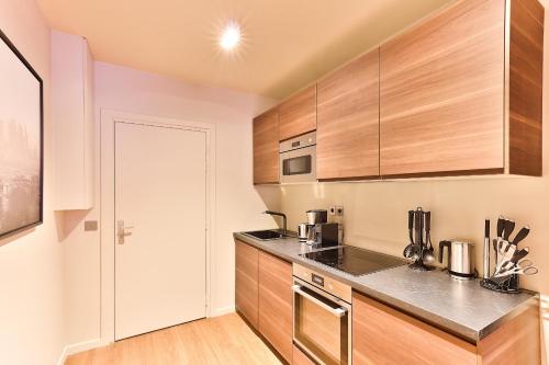 une cuisine avec des armoires en bois et des appareils en acier inoxydable dans l'établissement 111- Urban Théâtre de la Madeleine, à Paris