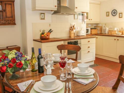 a kitchen with a wooden table with plates and wine glasses at Penymaes in Chirk