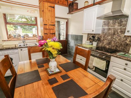 a kitchen with a table with a vase of flowers on it at Horrace Farm Cottage in Pennington