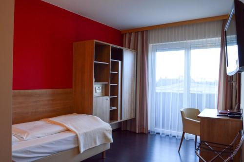 a bedroom with a bed and a desk and a window at Hotel Römerhof in Tulln