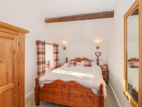 a bedroom with a wooden bed and a mirror at Bod Rhiw in Llandegwning