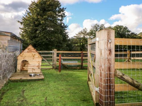 a wooden fence with a dog house in a yard at Higher Whiddon Farm Whiddon Well in Ashburton