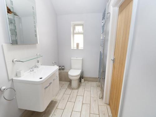 a white bathroom with a toilet and a sink at Jack's Corner in Grimston