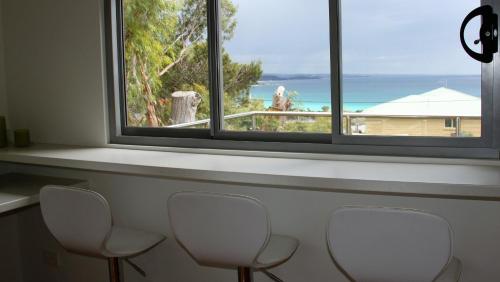 a row of chairs in a room with a window at BAY OF FIRES BEACH SHACK ocean views from a modern Beachhouse in Binalong Bay