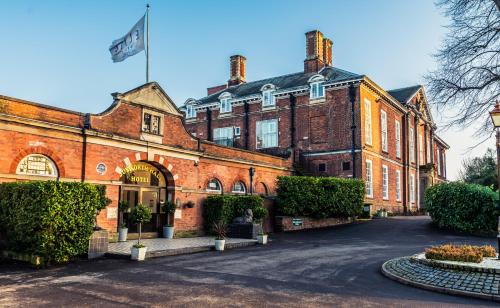 a large red brick building with a flag on it at Bosworth Hall Hotel & Spa in Market Bosworth