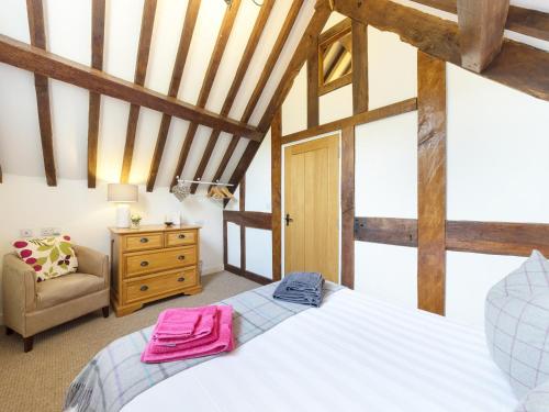 um quarto com uma grande cama branca e uma cadeira em Grafton Mill em Grafton Flyford