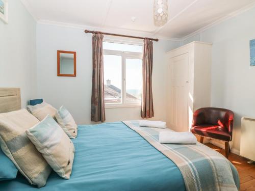 a bedroom with a large blue bed with a window at Highdown in Bigbury on Sea