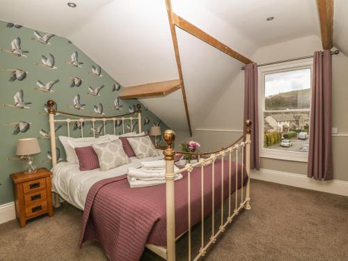 a bedroom with a bed and a window with birds on the wall at Talbot House in Castleton