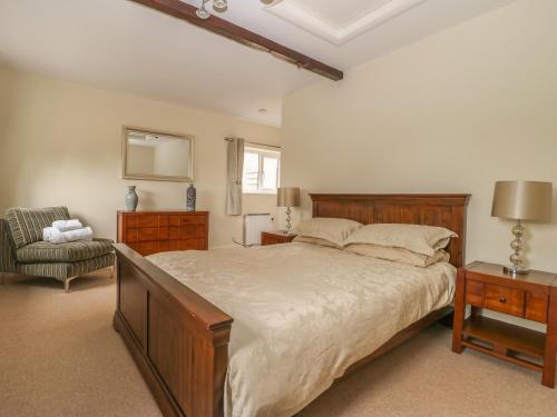 a bedroom with a large bed and a chair at The Paddock in Wheldrake