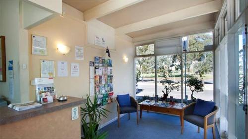 a waiting room with two chairs and a desk and a window at Parkville Motel in Melbourne