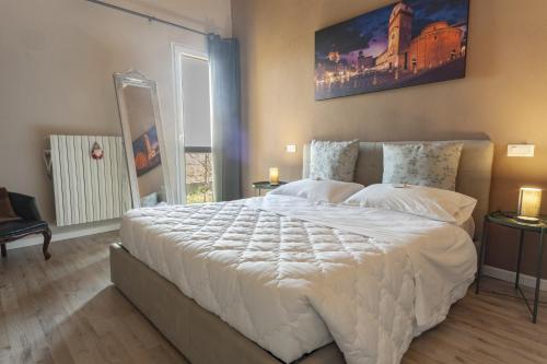 een slaapkamer met een groot wit bed met 2 lampen bij Corte castella in Mantova