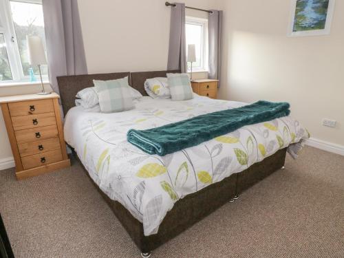 a bedroom with a bed with a green blanket on it at Glan Y Gors Cottage in Llangerniew