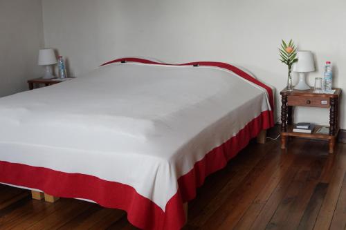 a bed with a red and white blanket and two tables at Lovasoa 4C in Antsirabe