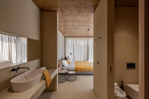 a bathroom with a tub and a bedroom with a bed at Herdade da Malhadinha Nova - Relais & Châteaux in Albernoa