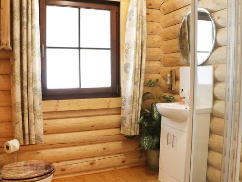 ein Badezimmer mit Holzwänden, einem Fenster und einem Waschbecken in der Unterkunft Wilderness Lodge in Shelve