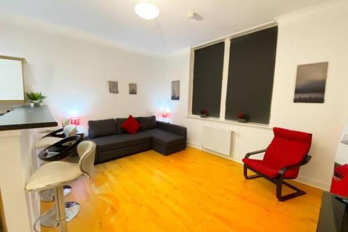 a living room with a black couch and a red chair at Cozy Nights - Ibrox Street in Glasgow