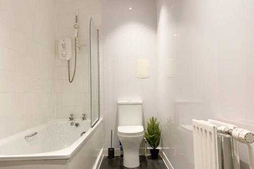 a white bathroom with a toilet and a bath tub at Cozy Nights - Ibrox Street in Glasgow