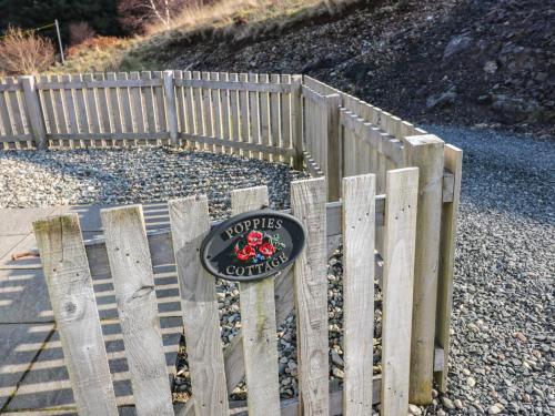 a wooden fence with a sign on top of it at Poppies Cottage in Craignure