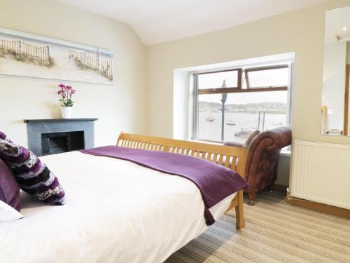 a bedroom with a bed with a fireplace and a window at Jasmin Cottage in Conwy