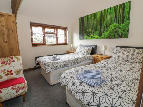 a bedroom with two beds and a chair at Duckling Barn in Bacton