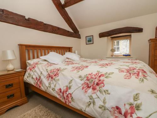 um quarto com uma cama com colcha floral em Brookside Barn em Bradwell