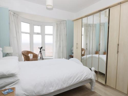 - une chambre avec un lit blanc et un grand miroir dans l'établissement Number Fifteen, à Withernsea