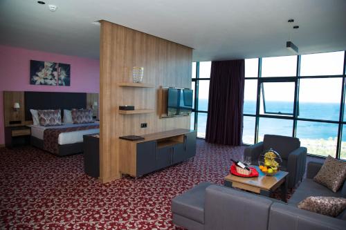 a hotel room with a bed and a living room at Euphoria Batumi Convention & Casino Hotel in Batumi