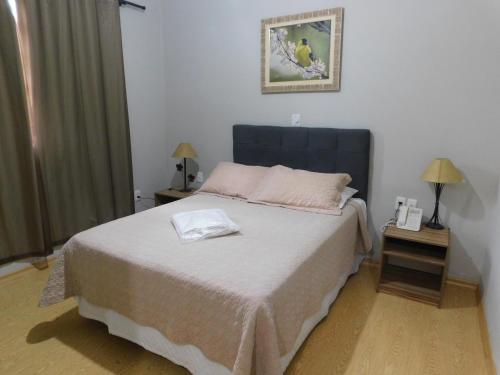 a bedroom with a large bed and two tables with lamps at Hotel Real São Lourenço in São Lourenço