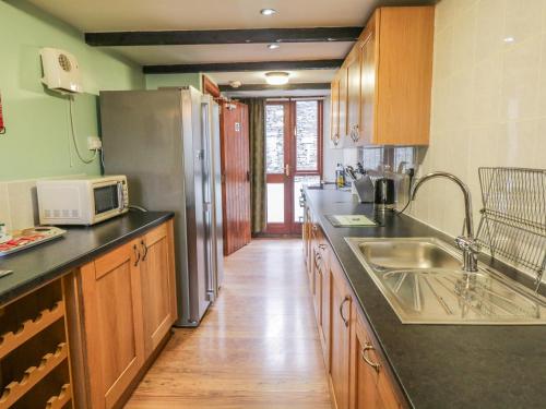 a kitchen with a sink and a refrigerator at Bank End Barn in Grizebeck