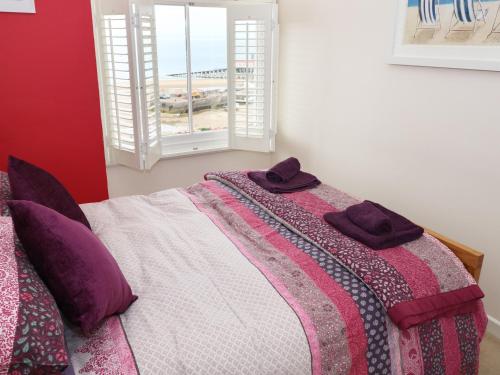 テンビーにある1 Beachtop Courtのベッドルーム1室(紫色の枕が付くベッド1台、窓付)