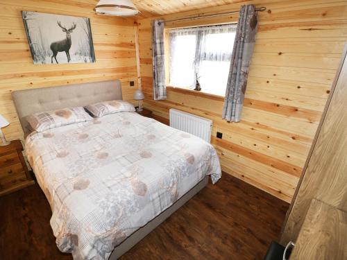 1 dormitorio con 1 cama en una cabaña de madera en Hayfields, en Grimston