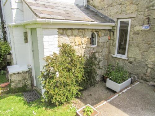 a stone house with a white door and some plants at Sweet Briars in Chalegreen