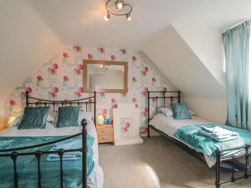 two beds in a attic bedroom with a mirror at Fishermans Rest in Burghead