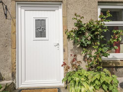 a white door on a house with a plant at Fishermans Rest in Burghead