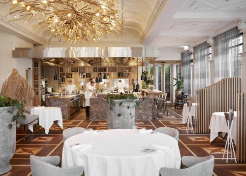 a restaurant with white tables and chairs and a chandelier at Grand Resort Bad Ragaz in Bad Ragaz