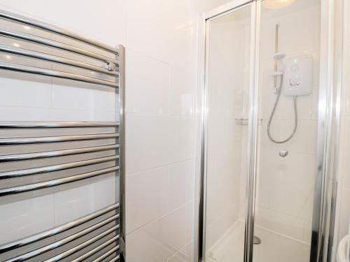 a shower in a bathroom with white walls at Sunnie Cottage in Seahouses